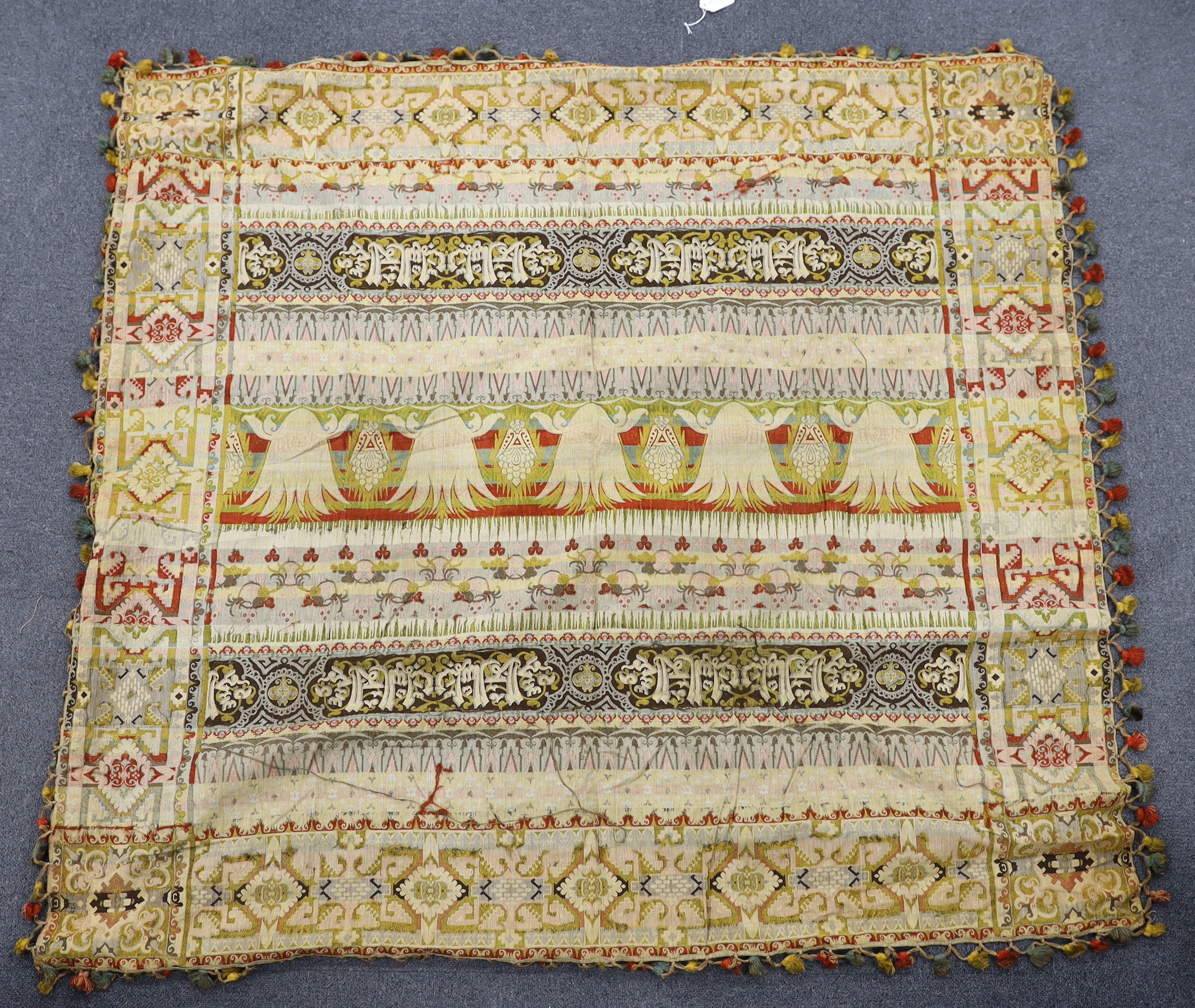 An Indian gold thread and coloured silk floss embroidered black wool cover with gold thread fringing and a later woven cover with bobble edging, black and gold cover 172cm x 169cm
